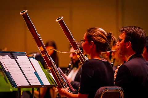 Woodwind players pause as they examine their sheet music during a performance