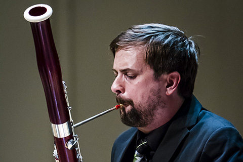 Musician in a dark suit plays the Bassoon