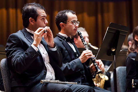 Classical musicians play wind instruments during a performance